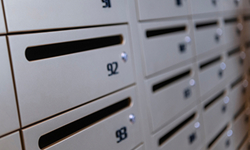 Close-up of numbered metal post office boxes with horizontal mail slots.